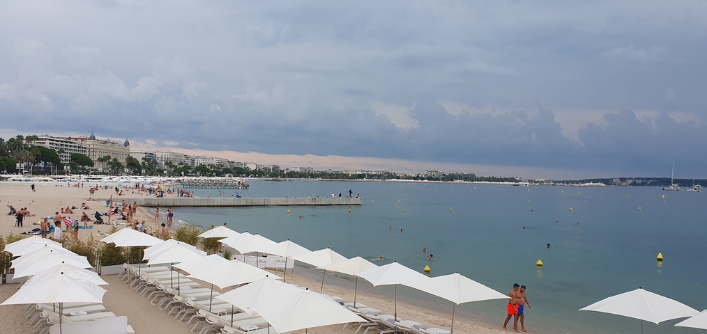 Beach with lounge chairs and people swimming in the sea.