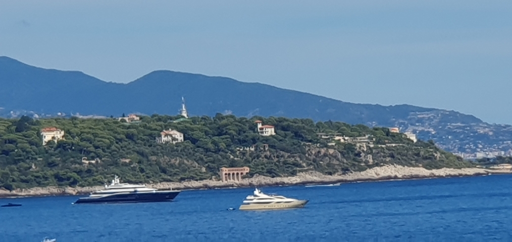       Yachts in the sea with green hills in the background.
  