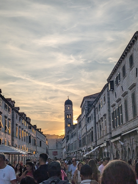 Sunset over a city with historic buildings and a bell tower.
