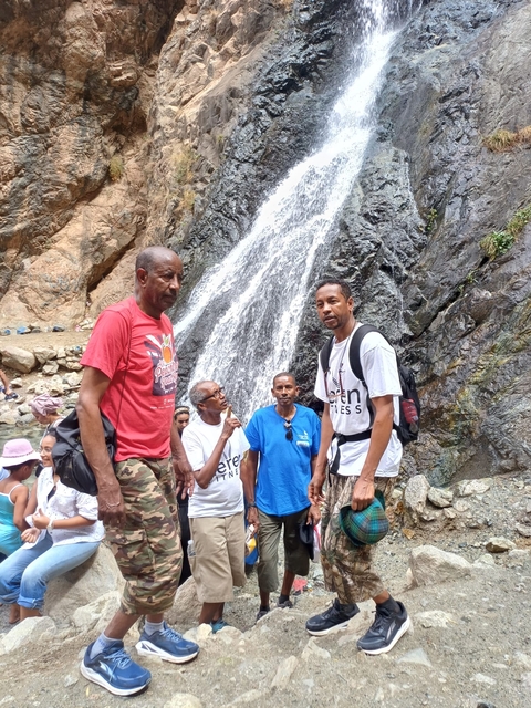       Group of people standing in front of a waterfall.
  