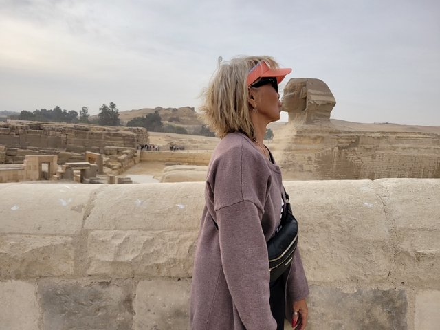 Person posing with the Sphinx and Pyramids in the background.