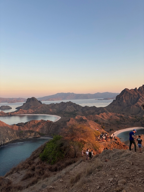Scenic view of a mountainous landscape by the sea during sunset.