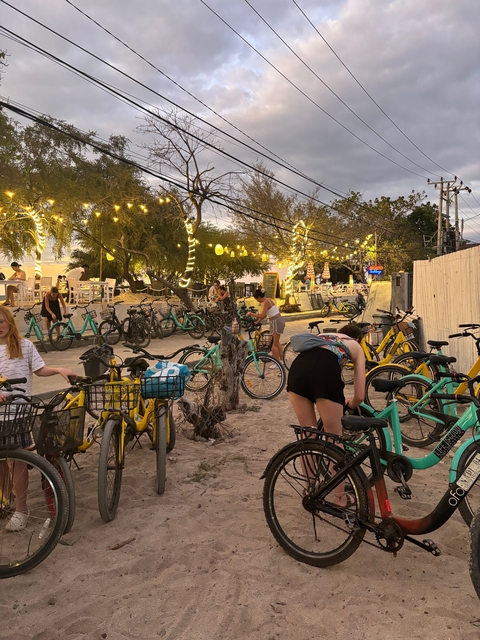 Bicycles parked under string lights at a lively outdoor venue.