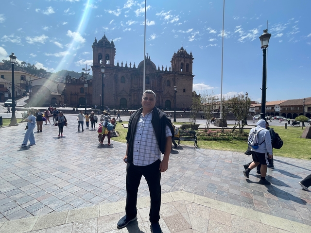       A man standing in a plaza with an ornate cathedral in the background.
  