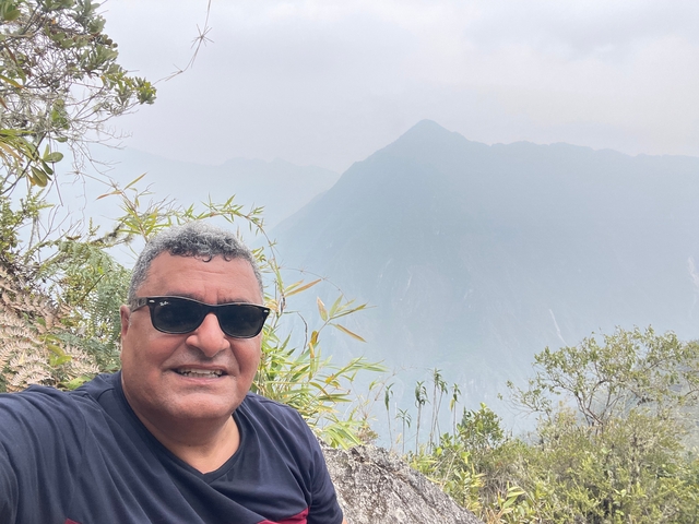       Person taking a selfie with misty mountains.
  