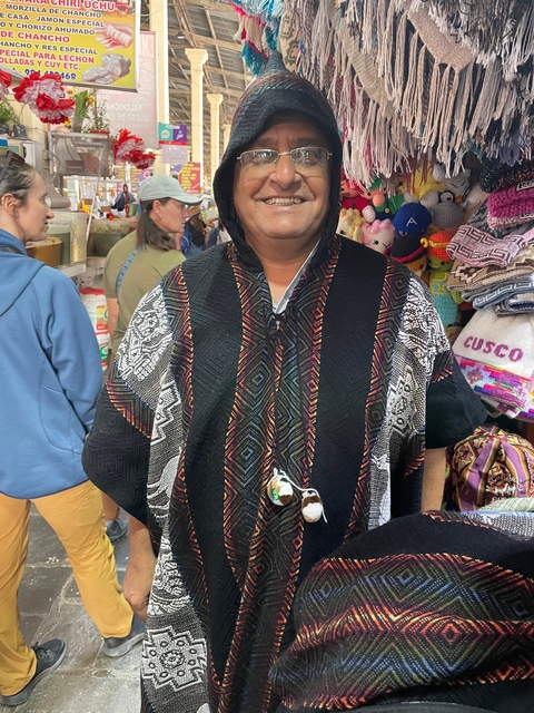       People wearing traditional clothing in a market setting, with textiles displayed.
  