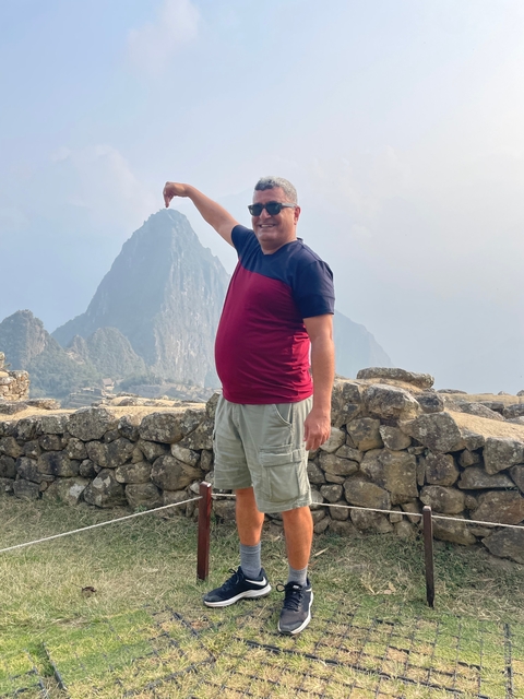       A man standing with Machu Picchu in the background.
  