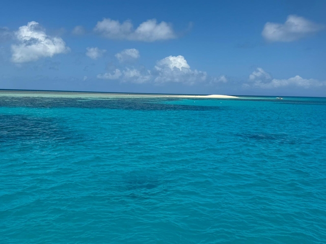       Clear blue ocean with a sandy island.
  