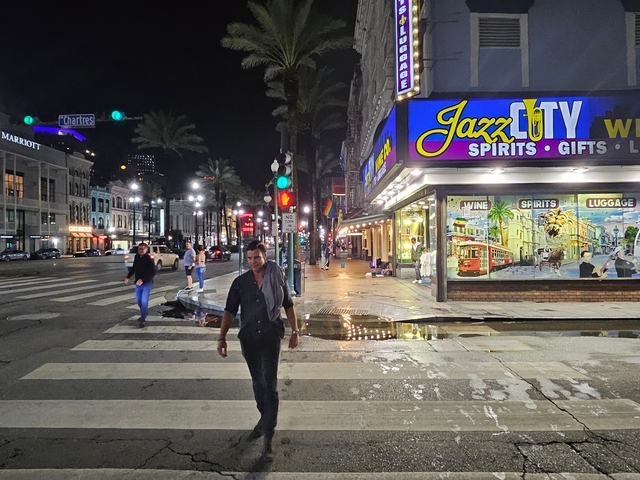 Busy street in New Orleans at night with neon signs.