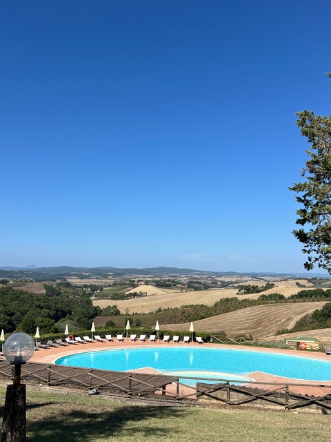Rolling hills and scenic landscape under a clear blue sky in Tuscany.