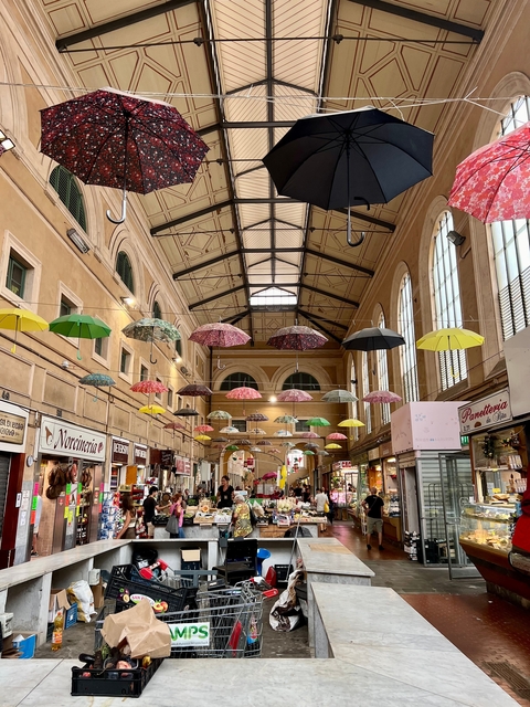 Indoor market with colorful umbrellas suspended from the ceiling.