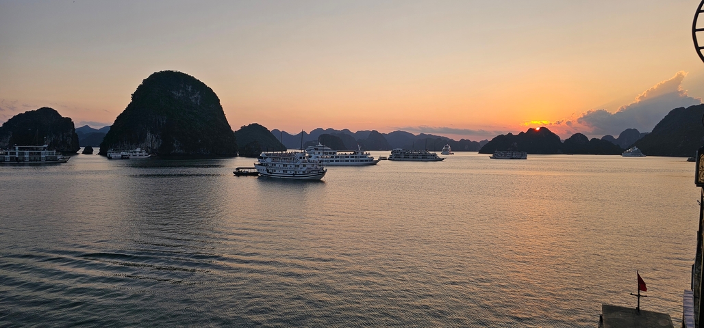 Halong Bay with boats and karst formations at sunset.