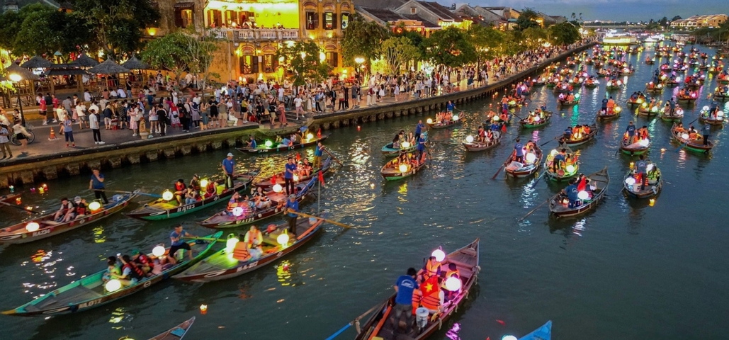 Evening view of a festival with boats and lanterns on a river.