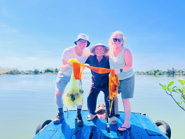      Couple holding a fishing net on a boat with a local.
  
