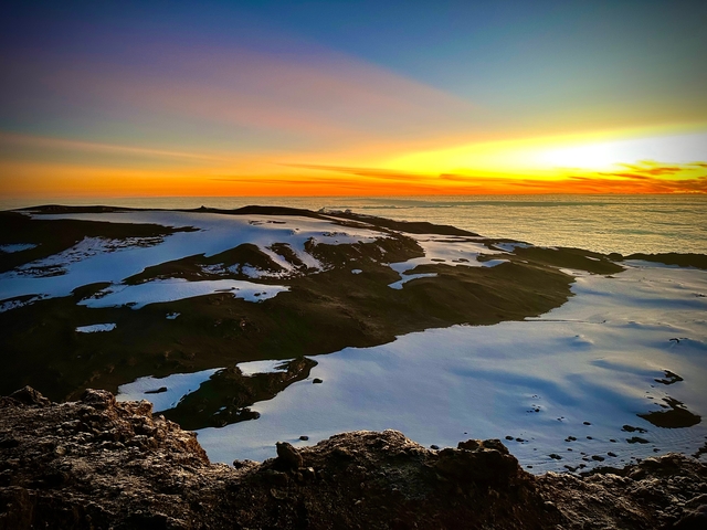 Sunrise over a snow-covered mountain landscape.