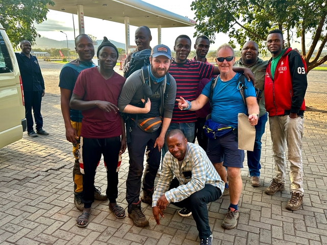 Group of people posing outside near a vehicle.