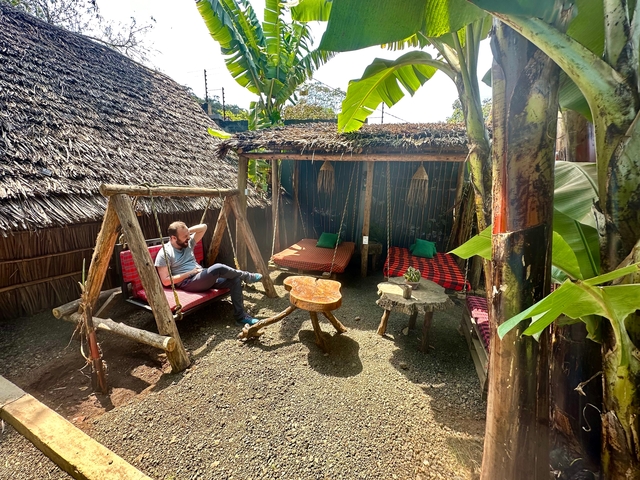 Man sitting in an outdoor relaxation area with wooden furniture.