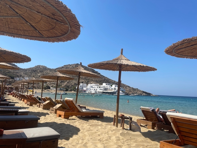 Beach with straw umbrellas and sun loungers facing the sea.