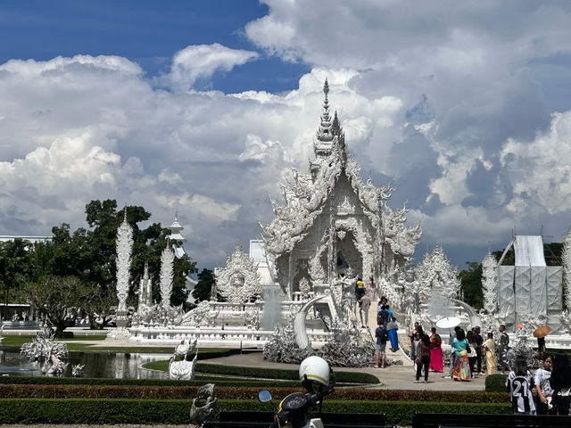       White ornate temple with people visiting.
  