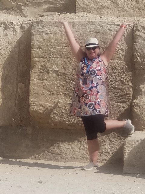 Person posing next to an ancient stone structure.