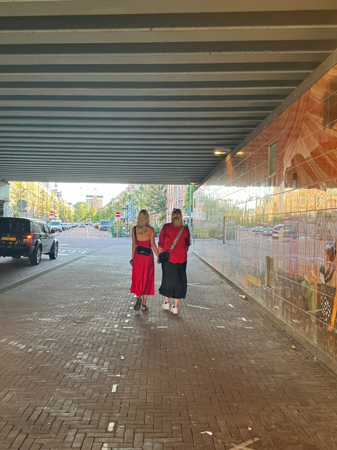 Two women walking hand in hand in an underpass.