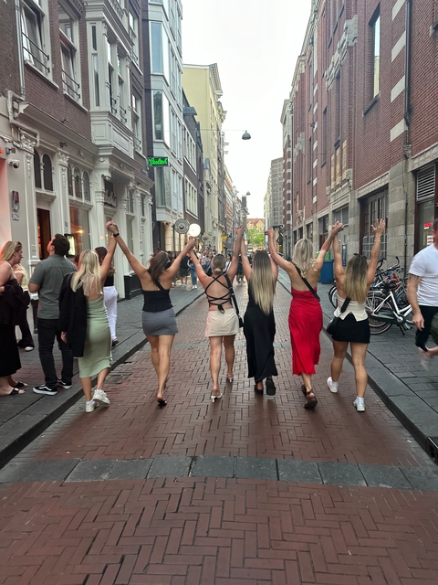 Five women walking down a city street with raised arms.