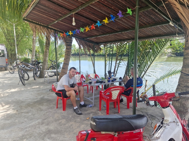 Two people relaxing at a riverside cafe with bikes.