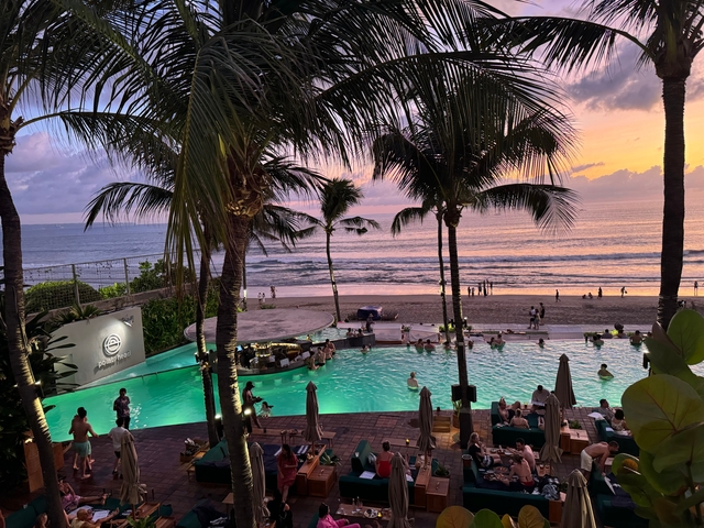Sunset view over a beachside pool with palm trees.