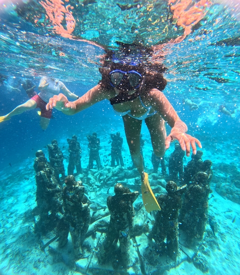 Snorkeling scene with underwater sculptures.