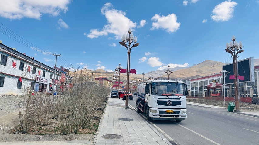 Street scene with a truck and buildings under a clear sky.
