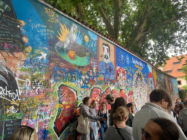 Brightly painted wall with graffiti and people gathered around.