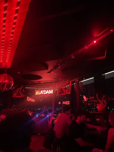 Interior of a dimly lit nightclub with red lighting and signs.