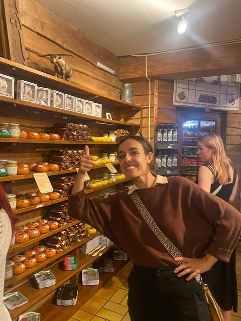 Person smiling and giving a thumbs up inside a shop selling preserves.