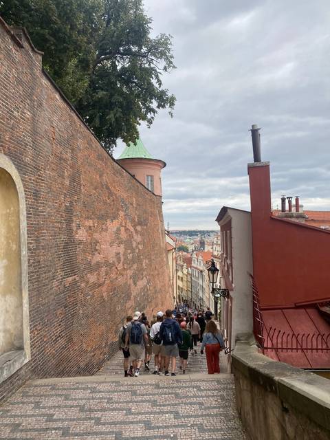 View down a sloped street with historical buildings in Prague.