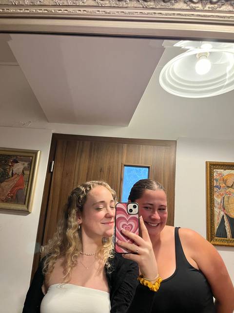 Two people taking a selfie in a bathroom mirror.