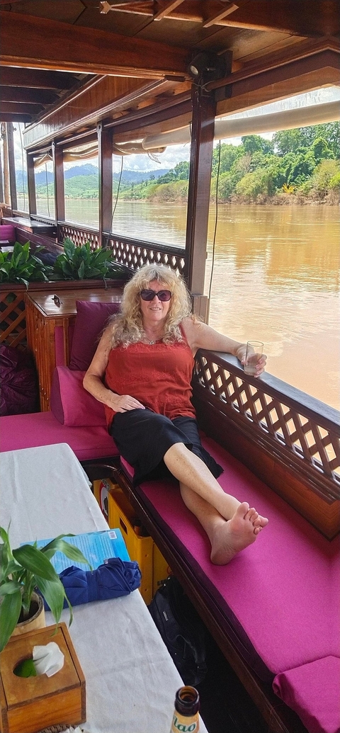       Person relaxing on a boat with a drink in hand.
  