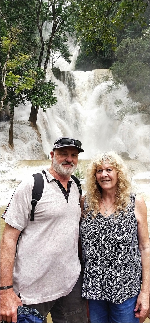       Two people posing in front of a waterfall.
  