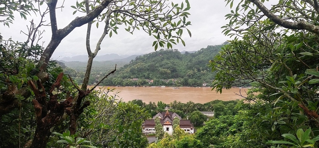       Scenic view of a river and mountains with a large building.
  