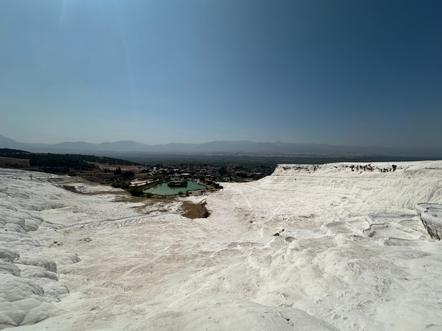Wide landscape of a natural white terrace formation with a distant town.
