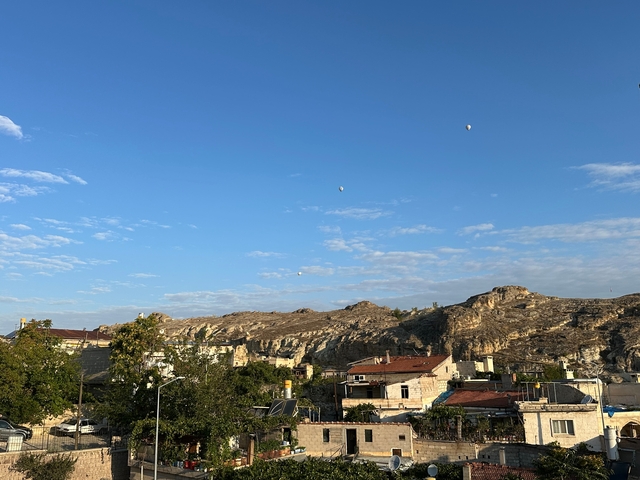 Landscape with rock formations and hot air balloons in the distance.