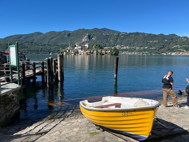Yellow rowboat on a lake with mountains and an island in the background.
