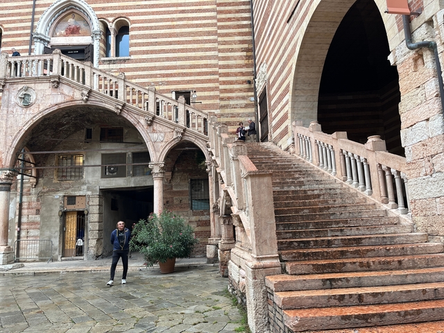       People on a historic staircase with arches, slightly different angle.
  