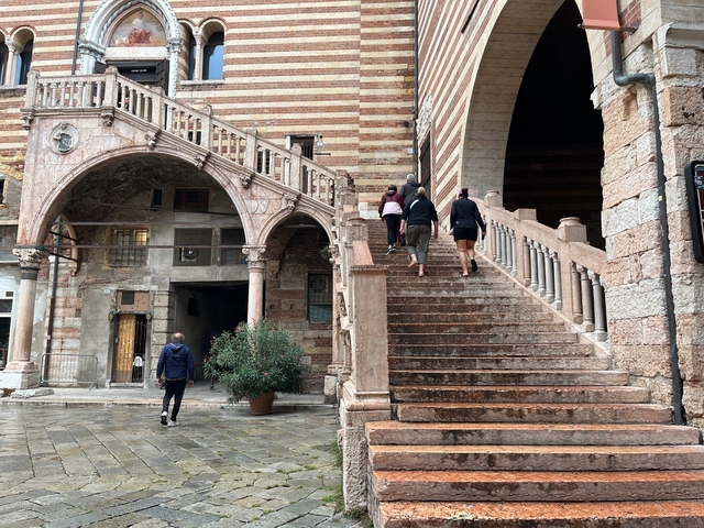 People climbing a historic staircase with arches.