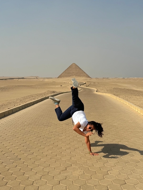      Person performing acrobatics in front of a pyramid.
  