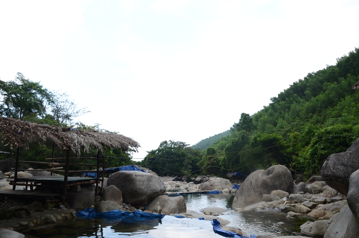 A natural pool surrounded by rocks and trees.