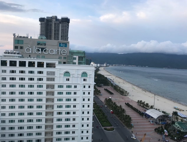 A view of a beachside hotel with the sea and mountains.