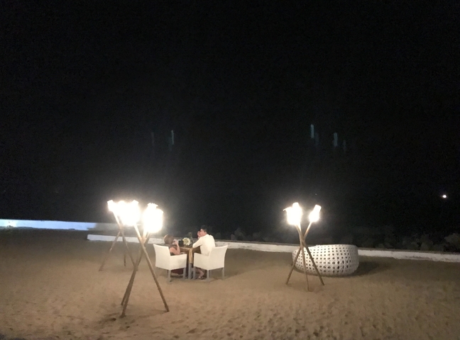 A romantic candlelight dinner setup on a beach at night.