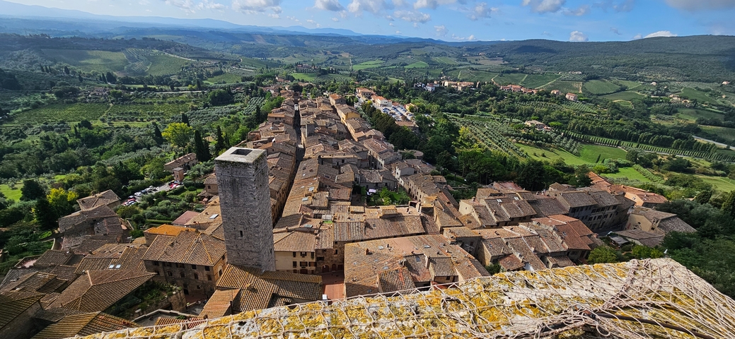       Panoramic view of a medieval town with a tall tower.
  