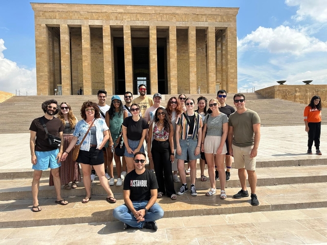 Group of people posing in front of a historic building with columns.