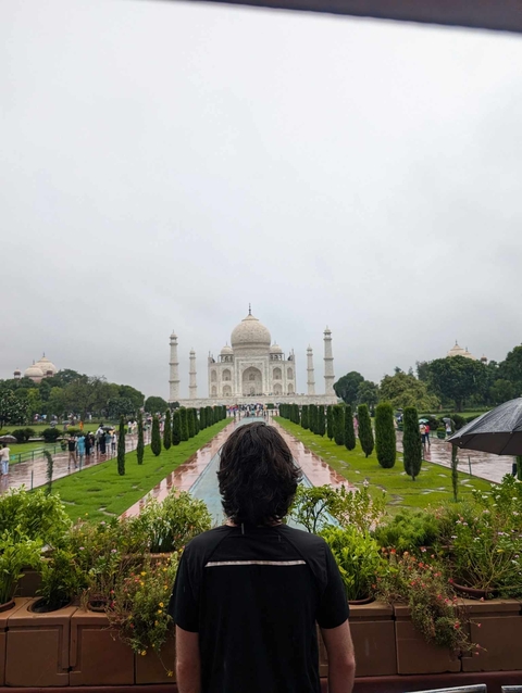       The Taj Mahal with tourists in the foreground on a cloudy day.
  